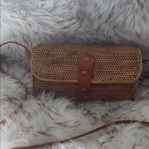Rattan crossbody bag with leather strap and clasp.